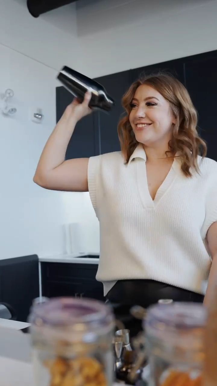 Hannah smiling as she shakes a cocktail shaker behind the bar